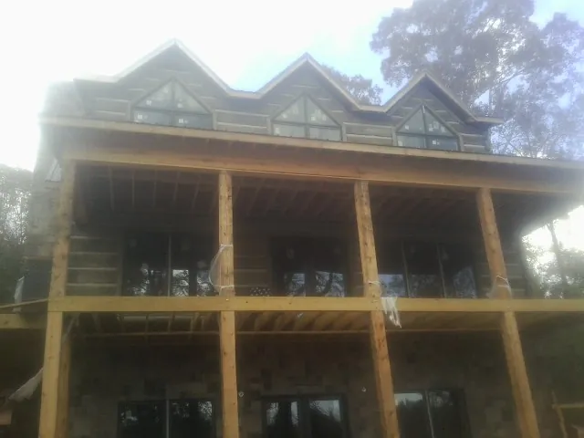 Dormers and porch framing on a large log home under construction — Roof Coating work by our crew in Monona