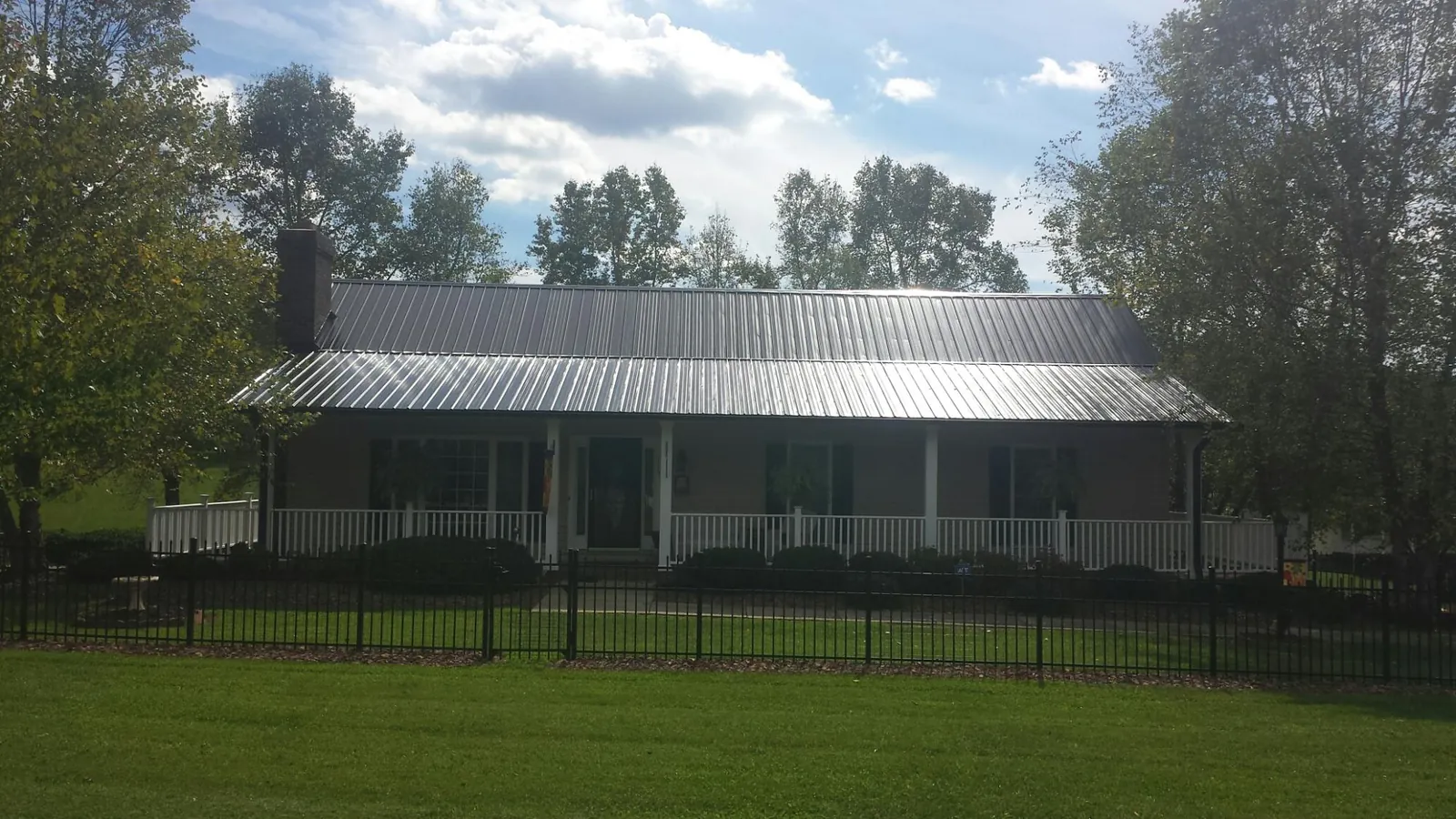 Gray metal roof on a brick ranch with a full width front porch — Gutter Guard Installation work by our crew in Monona