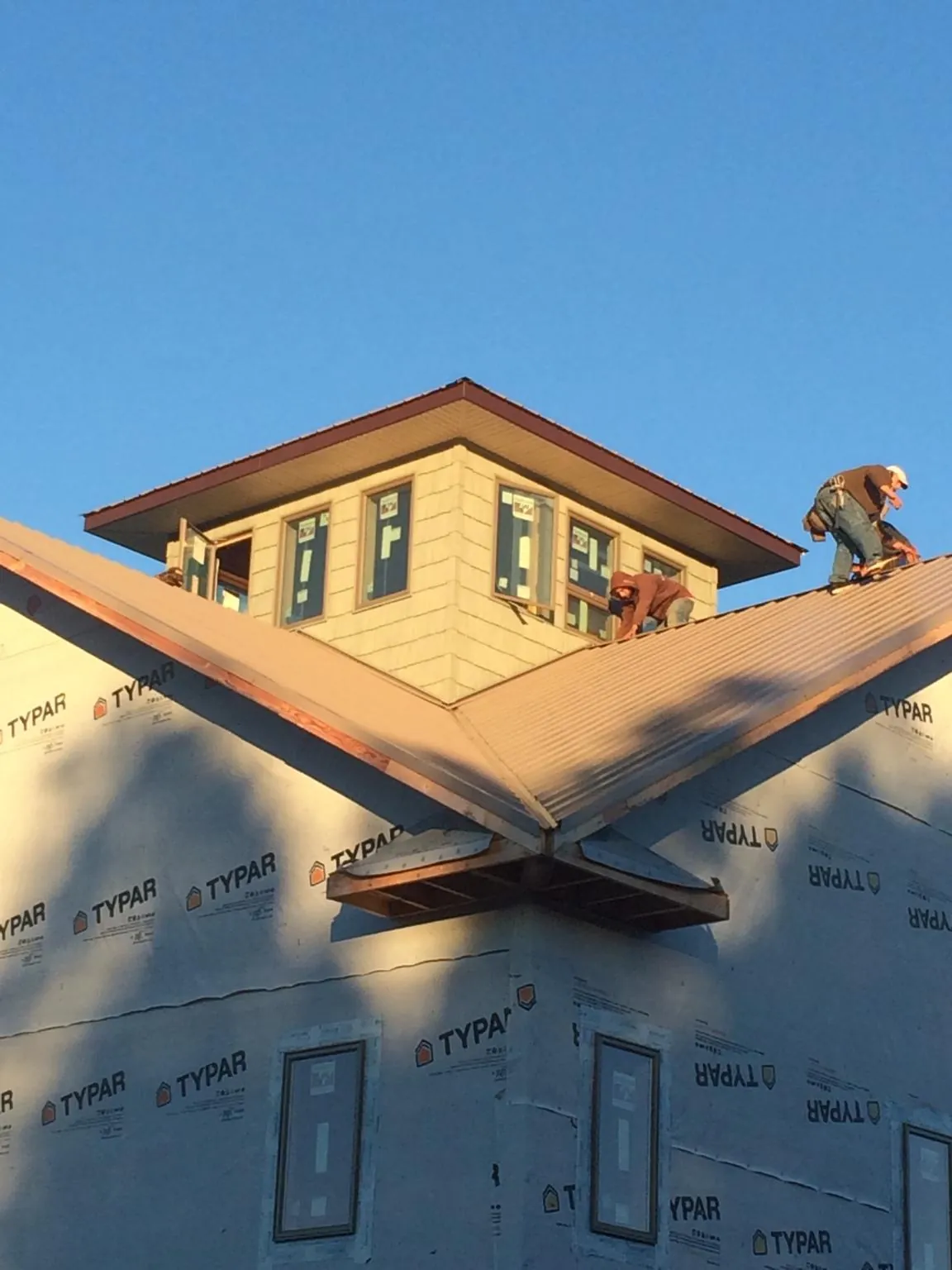 Roofers working around a rooftop cupola on a new metal roof at sunset — Roof Waterproofing in Monona by Roofing Brothers
